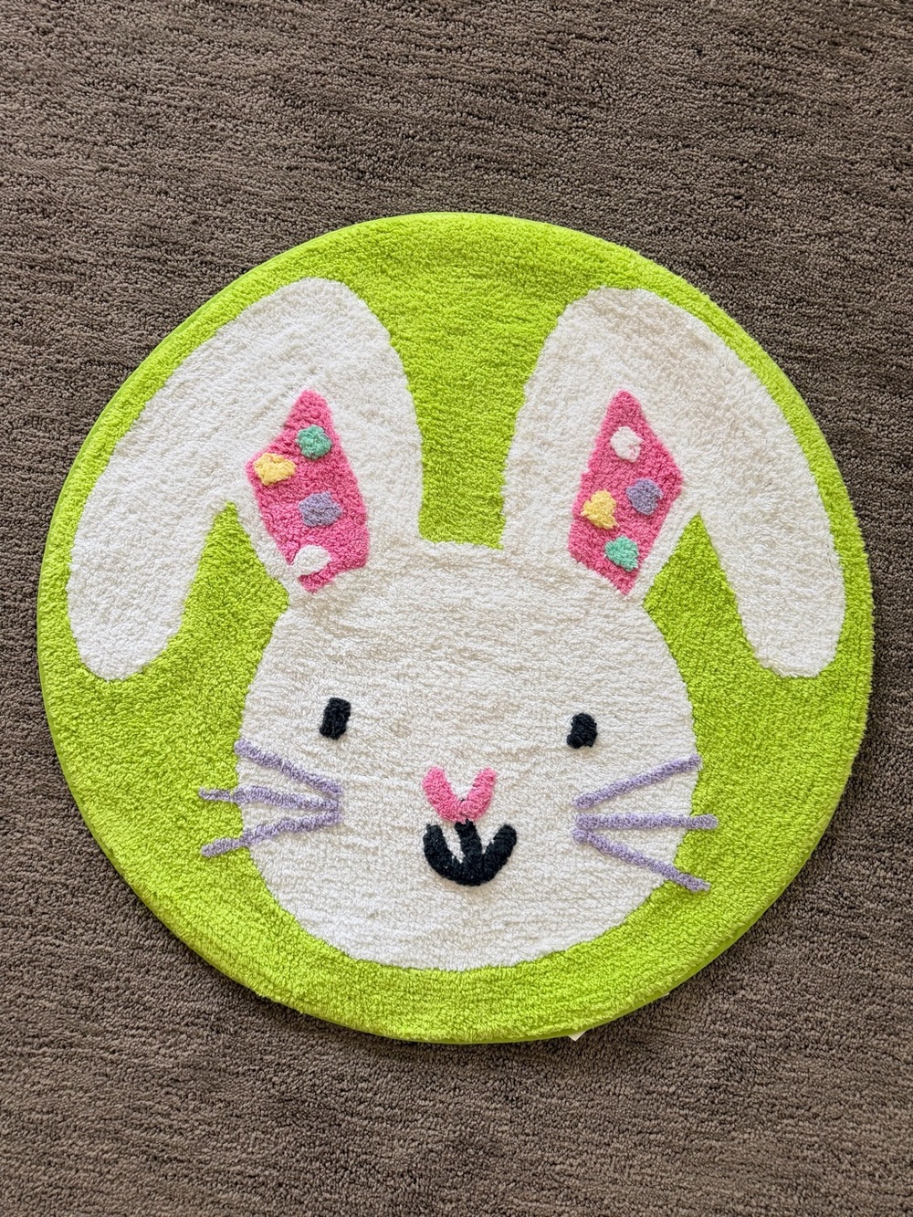 Round tufted bathroom mat with Easter bunny design in green, white, and pink